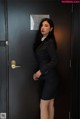 A woman in a business suit standing in front of a door.