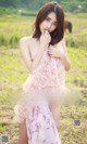 A woman in a pink dress standing in a field.