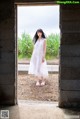 A woman in a white dress standing in an open doorway.