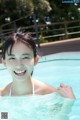 A young woman in a swimming pool smiling at the camera.