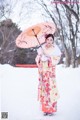 A woman in a kimono holding an umbrella in the snow.