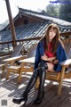 A woman sitting on a wooden deck wearing black boots.