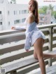 A woman in a white shirt is posing on a balcony.