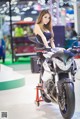 A woman in a black dress sitting on a motorcycle.