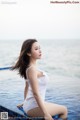 A woman in a white bathing suit sitting on the edge of a pool.