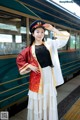 A woman in a red and white dress standing next to a train.