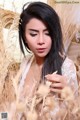 A woman in a white dress sitting in a field of tall grass.