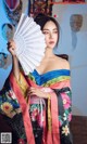 A woman in a kimono holding a fan in her hand.