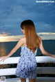 A woman in a blue and white dress standing on a balcony.