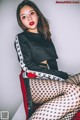 A woman sitting on top of a red chair wearing fishnet stockings.