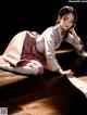 A woman in a kimono laying on a wooden floor.