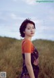 A woman standing in a field of tall grass.