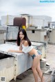 A woman in a white top and blue shorts posing on a roof.