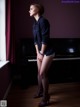 A woman standing in front of a piano in a room.