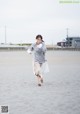 A woman running on a sandy beach with a white dress.