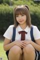 A young woman in a school uniform sitting on the grass.